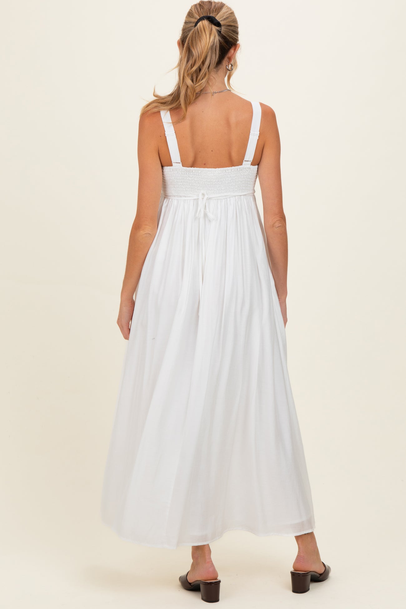 woman wearing a white maternity maxi dress with smocked back and adjustable straps, viewed from the back