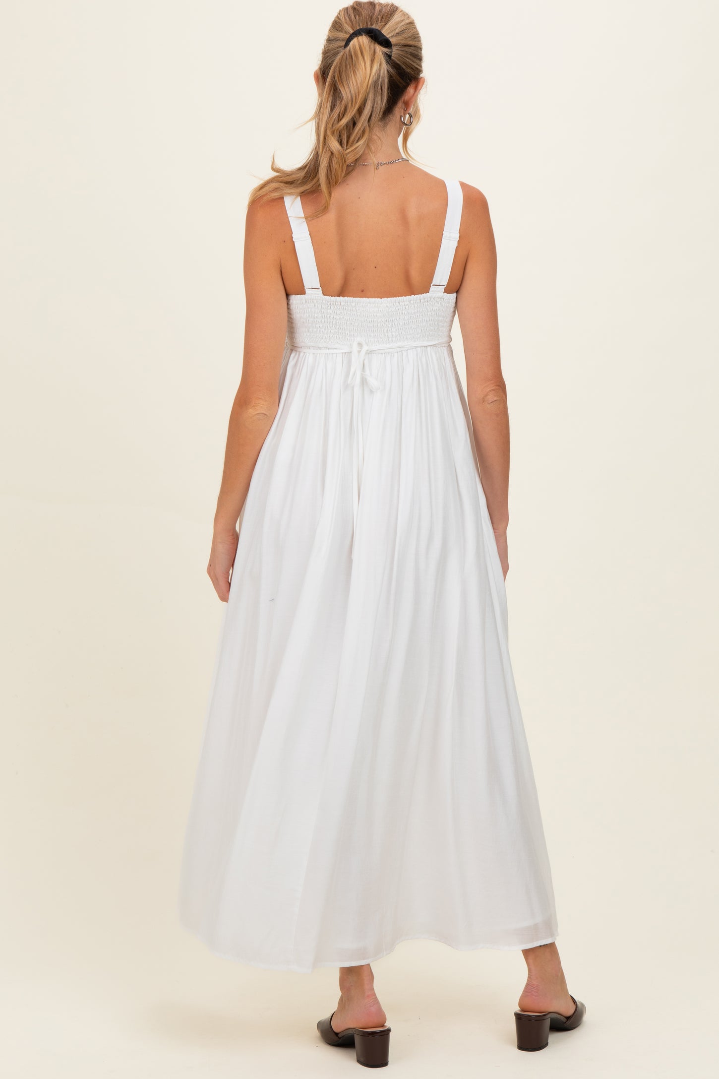 woman wearing a white maternity maxi dress with smocked back and adjustable straps, viewed from the back