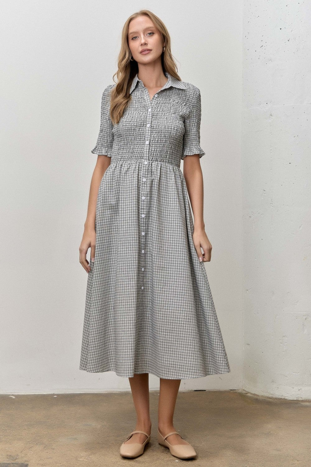 woman wearing a gray and white checked button-up dress with short sleeves and a gathered waist