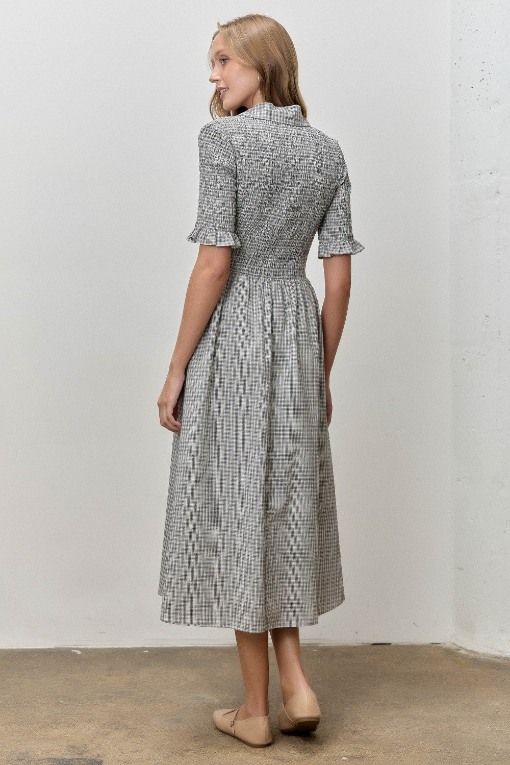 woman wearing a gray and white checkered midi dress with short sleeves and a cinched waist, viewed from the back