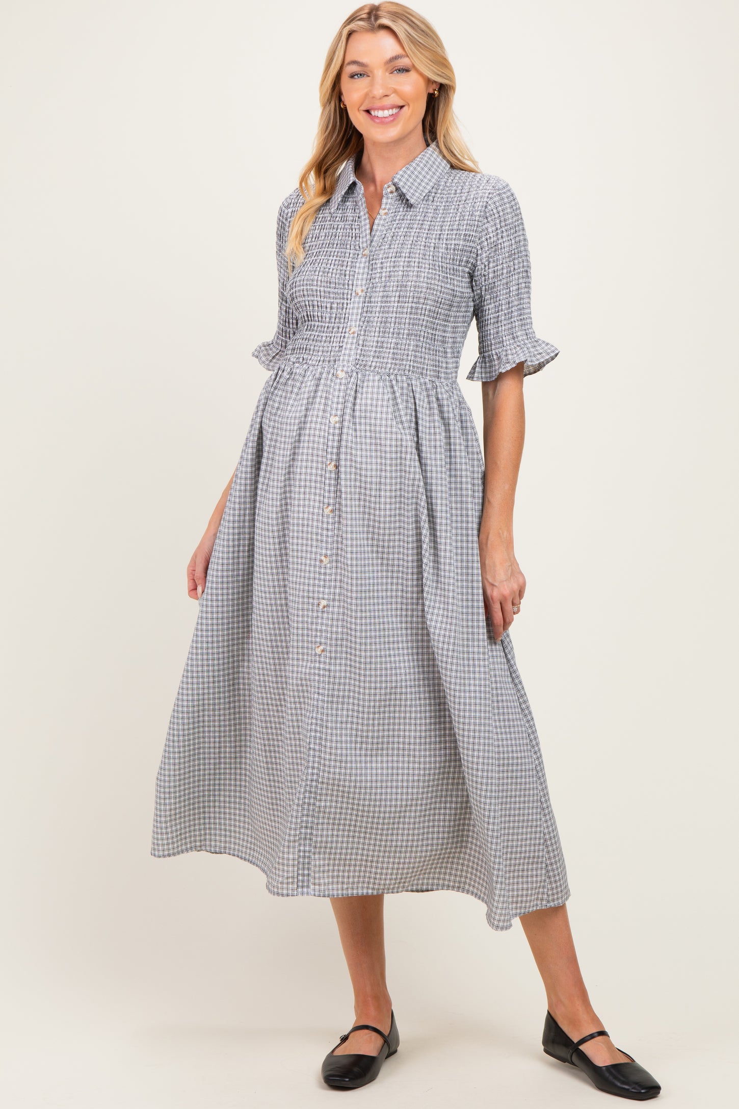 woman wearing a black and white gingham maternity dress with short sleeves and button-down front, showcasing a baby bump