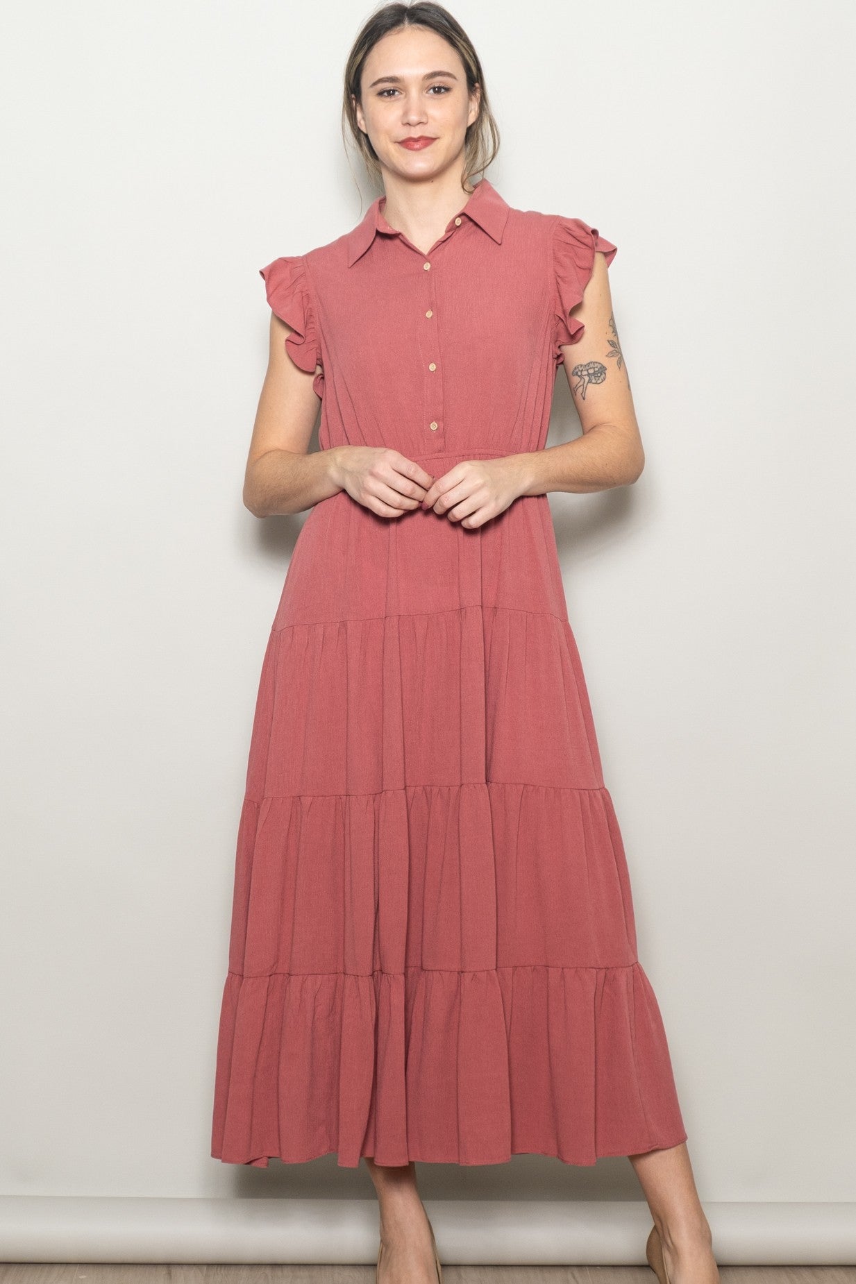 woman wearing a dusty rose tiered maxi dress with a collared neckline and ruffle sleeve details