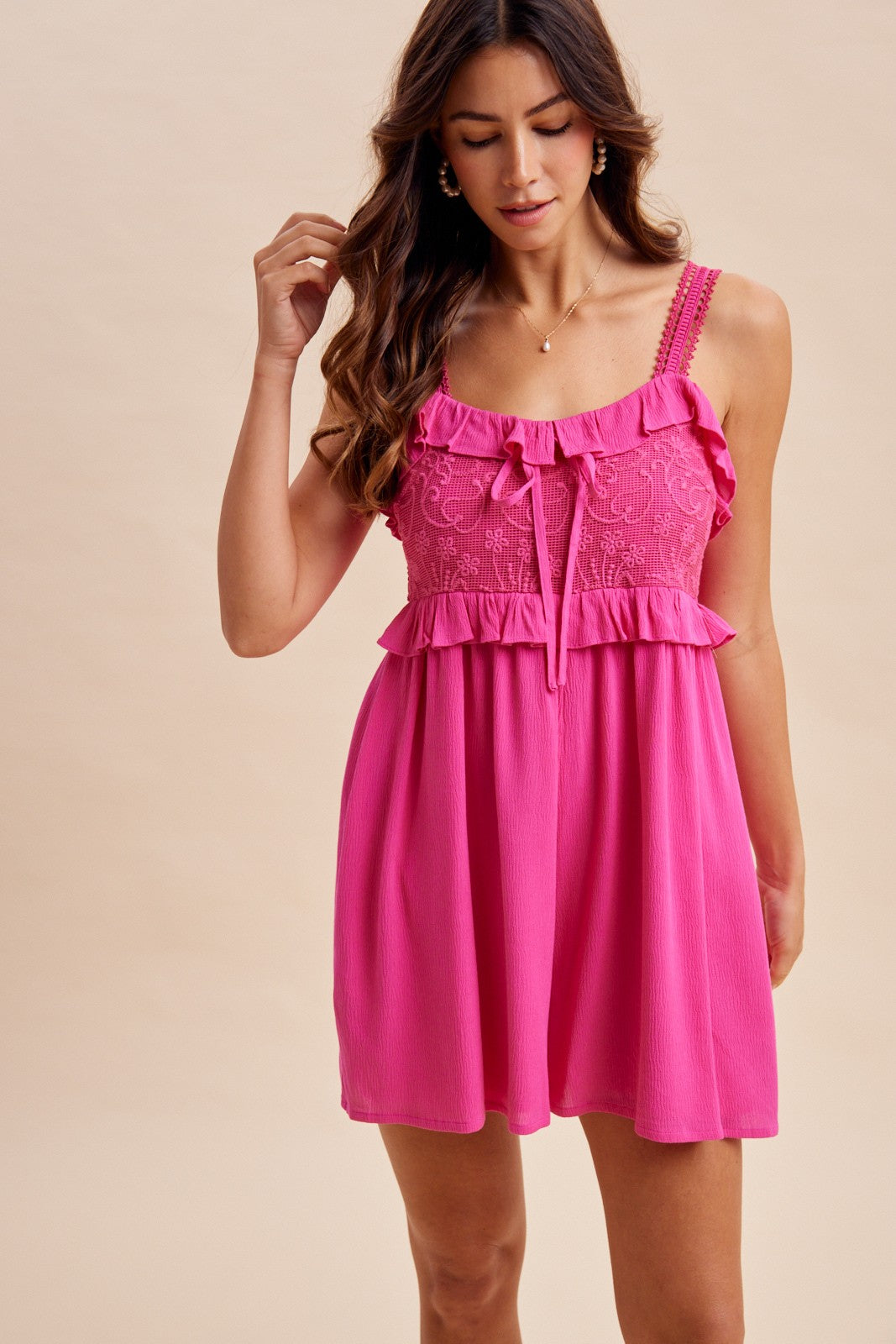 woman wearing a hot pink sleeveless dress with ruffled details and a tie-front design