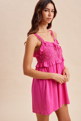 woman wearing a bright pink sundress with ruffle details and decorative straps