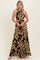 woman wearing a black and tan floral print halter maxi dress with cut-out details and a flowing skirt