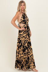 woman wearing a black and tan floral print halter dress with cut-out sides and a tiered skirt