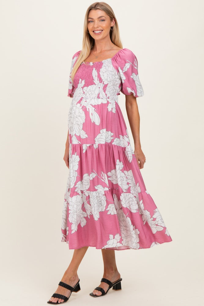 woman wearing a pink floral maternity dress with puff sleeves and a fitted bodice, showcasing her baby bump