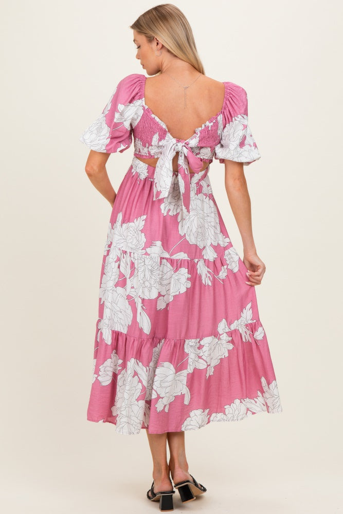 woman wearing a pink floral maternity maxi dress with puff sleeves and a tied back detail, showcasing a baby bump