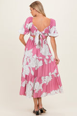 woman wearing a pink floral maternity maxi dress with puff sleeves and a tied back detail, showcasing a baby bump