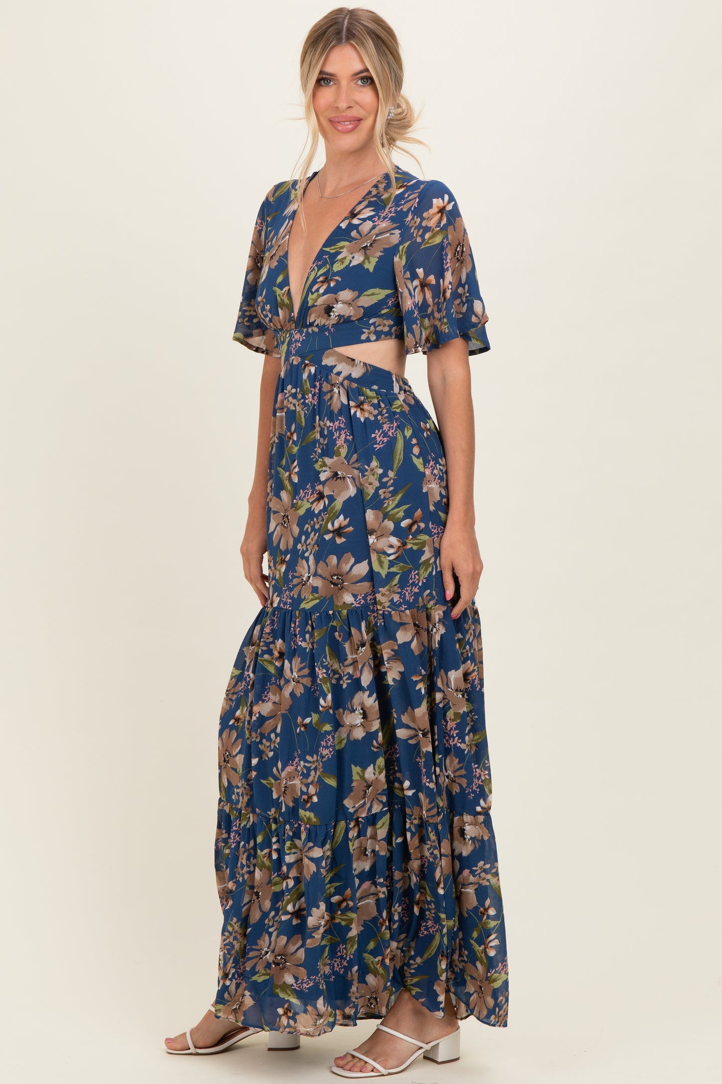 woman wearing a navy blue floral maxi dress with a deep v-neck and flutter sleeves, posing gracefully