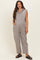 woman wearing a gray sleeveless maternity jumpsuit with hood and pockets, styled with sandals