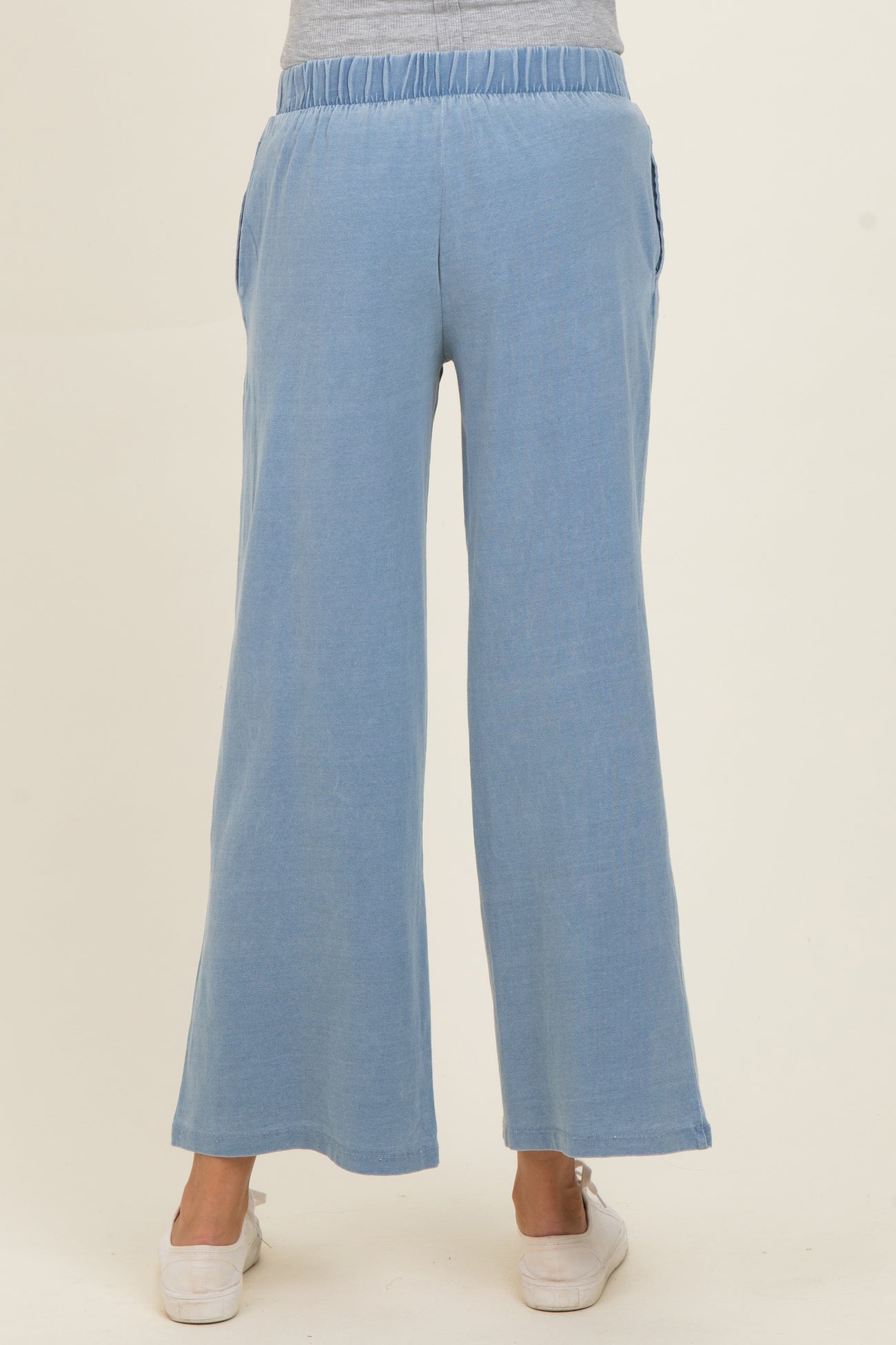 woman wearing light blue maternity wide-leg pants with elastic waistband and side pockets, showing a casual style from the back