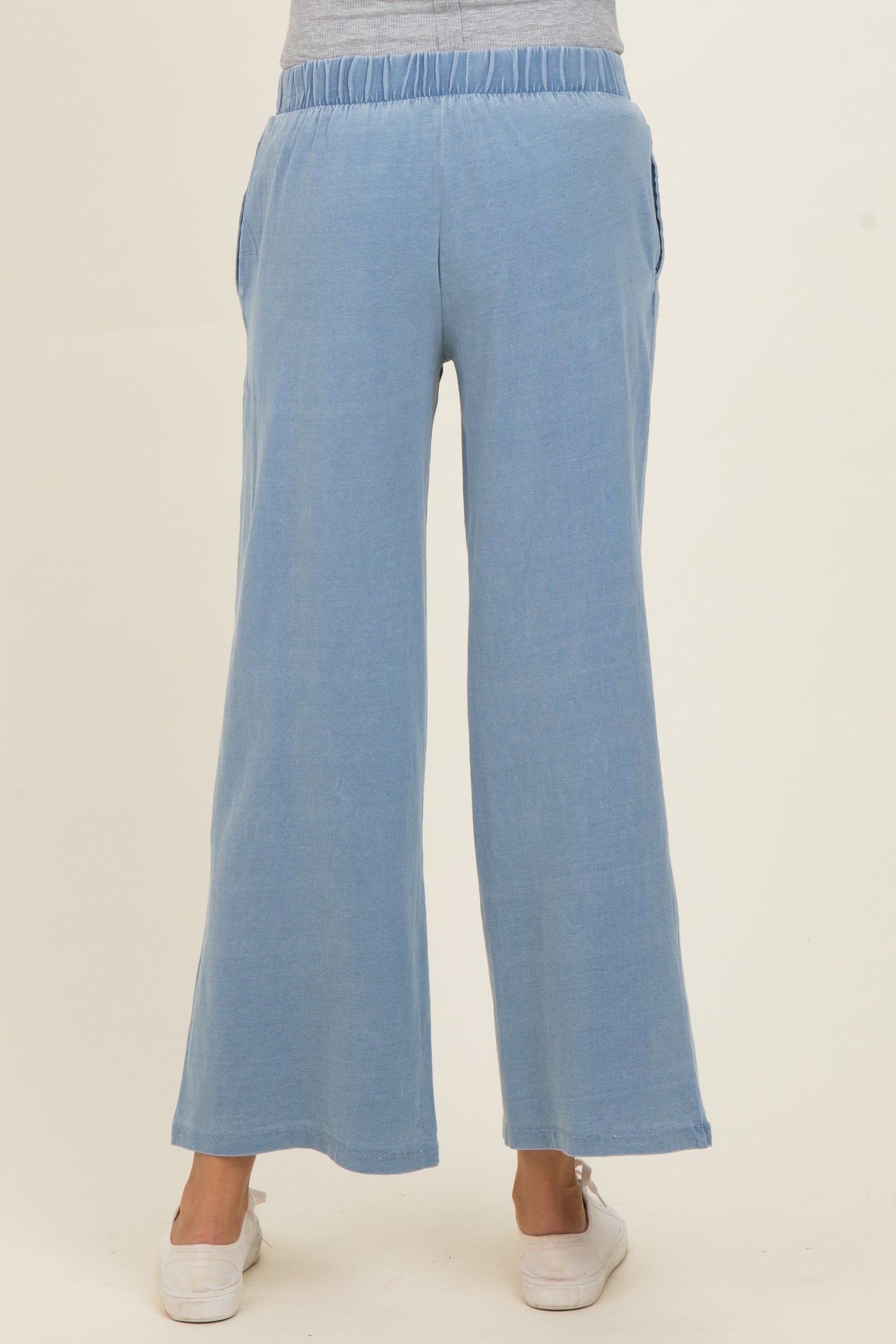 woman wearing light blue maternity wide-leg pants with elastic waistband and side pockets, showing a casual style from the back