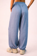 woman wearing light blue loose-fitting pants with an elastic waistband and cuffed ankles