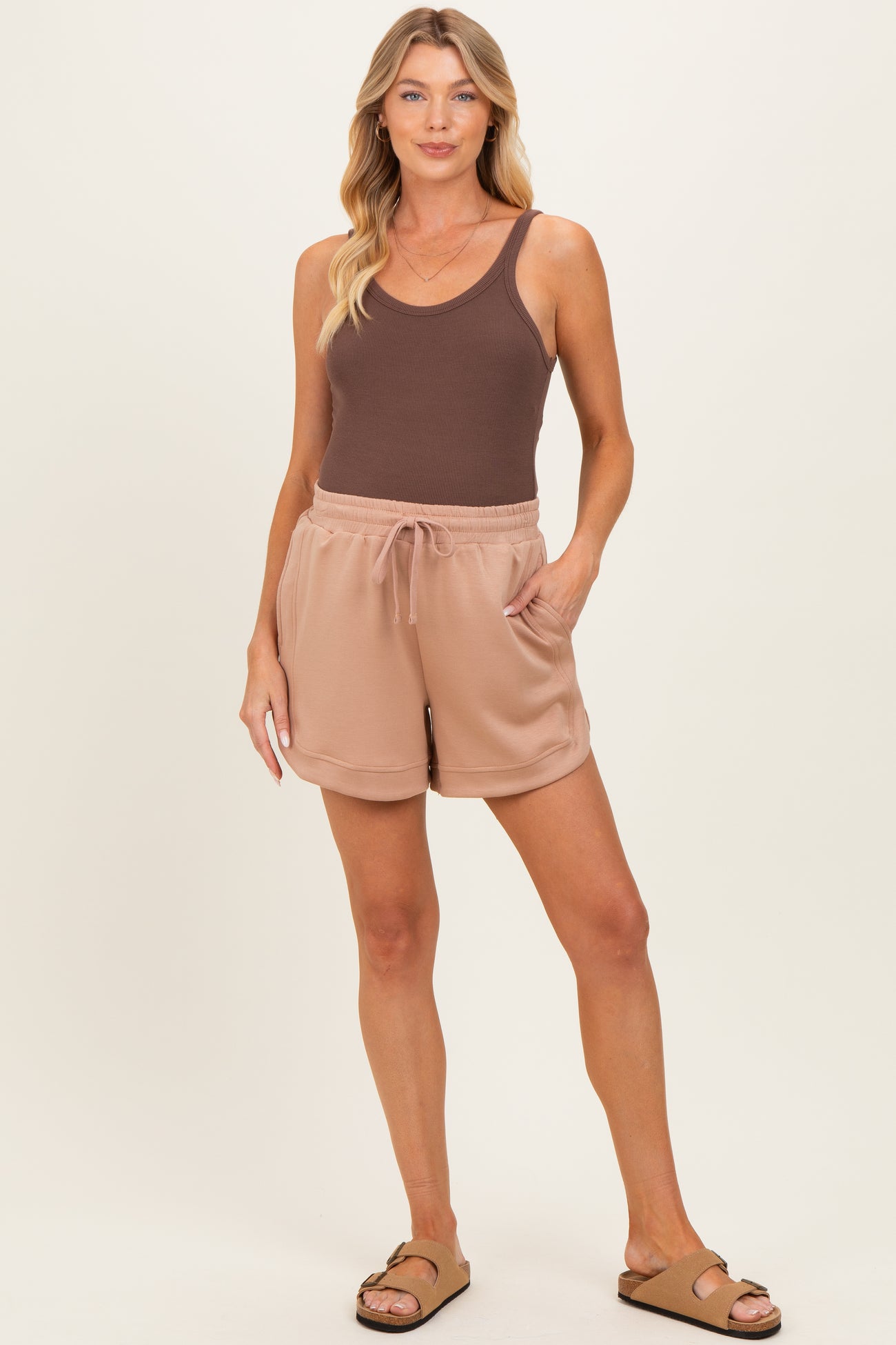 woman wearing a brown tank top and beige maternity shorts with a drawstring and pockets