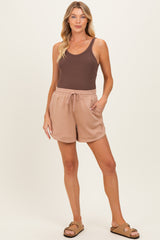 woman wearing a brown tank top and beige maternity shorts with a drawstring and pockets