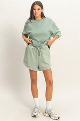 woman wearing a light green oversized t-shirt and matching shorts with an elastic waist and side pockets