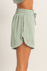 woman wearing light green drawstring shorts with side slits and a relaxed fit