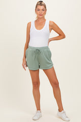 woman wearing a white tank top and mint green maternity shorts, styled with a relaxed fit and drawstring waistband