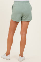 woman wearing light green maternity shorts, seen from the back, with pockets and an elastic waistband