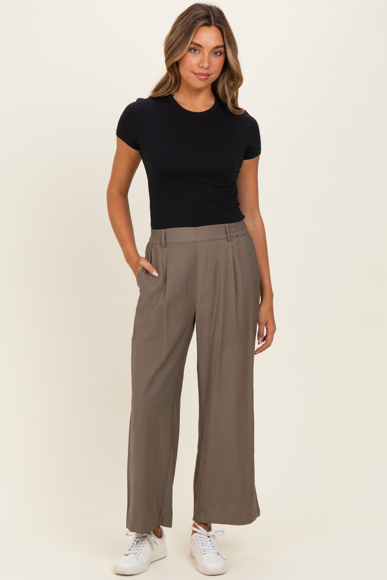 woman wearing a black fitted t-shirt and taupe wide-leg pants paired with white sneakers