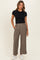 woman wearing a black fitted t-shirt and taupe wide-leg pants paired with white sneakers