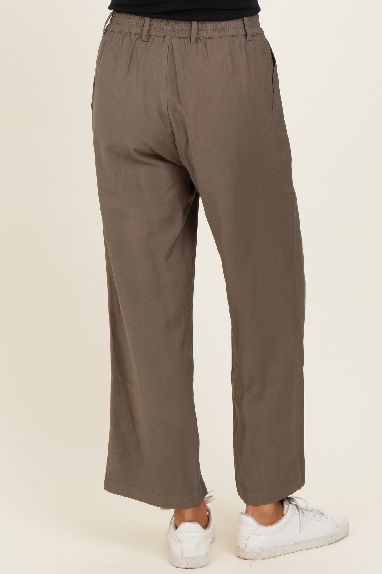 woman wearing olive green wide-leg trousers with an elastic waistband and side pockets, viewed from the back