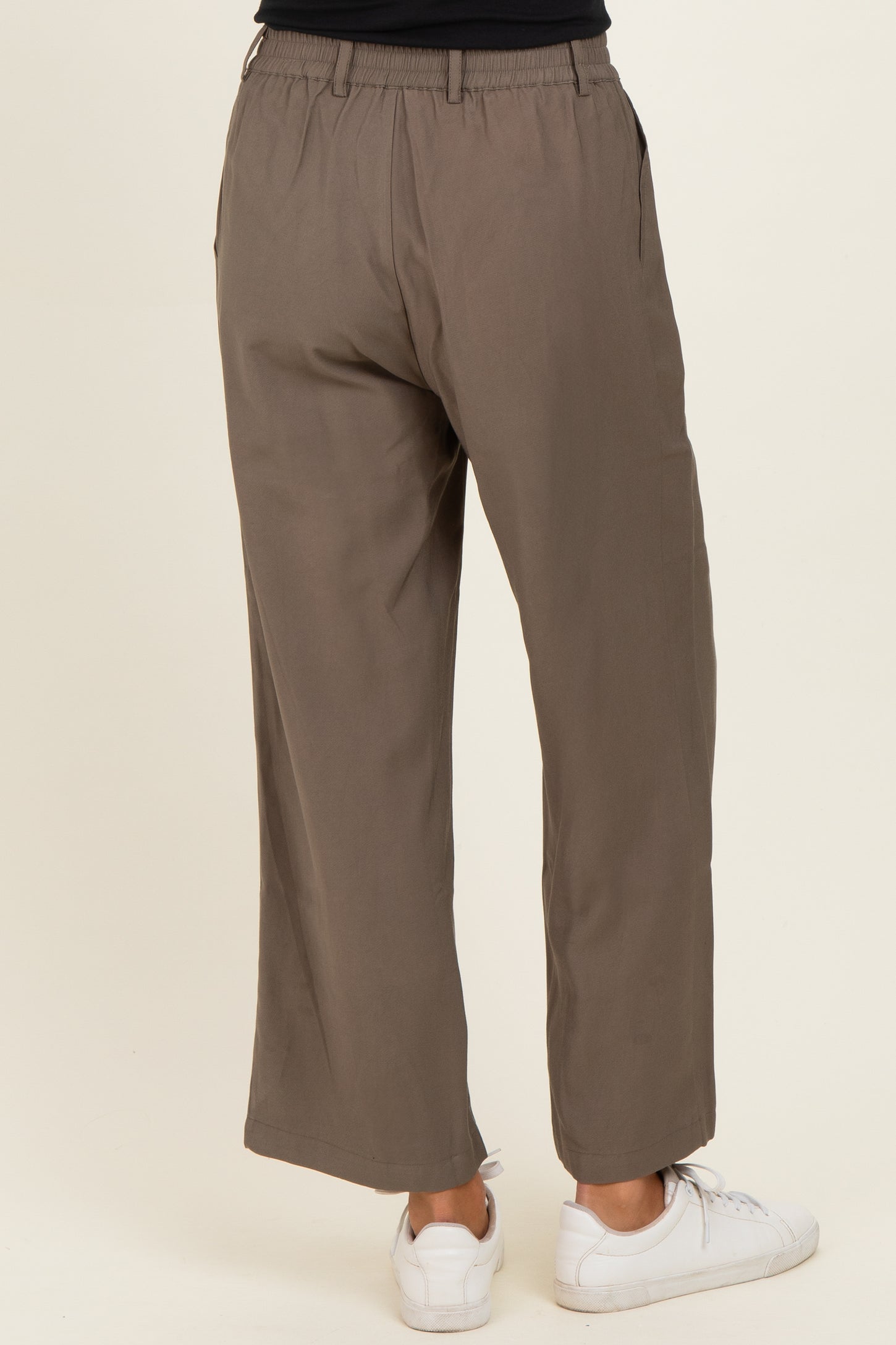 woman wearing olive green wide-leg trousers with an elastic waistband and side pockets, viewed from the back