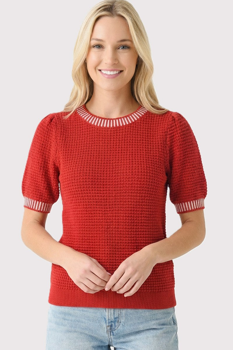 woman wearing a red short sleeve sweater with puffed sleeves and striped neckline, smiling at the camera