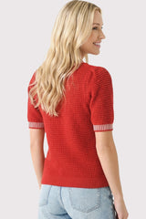 woman wearing a red textured short sleeve sweater with striped cuffs and a relaxed fit, seen from the back