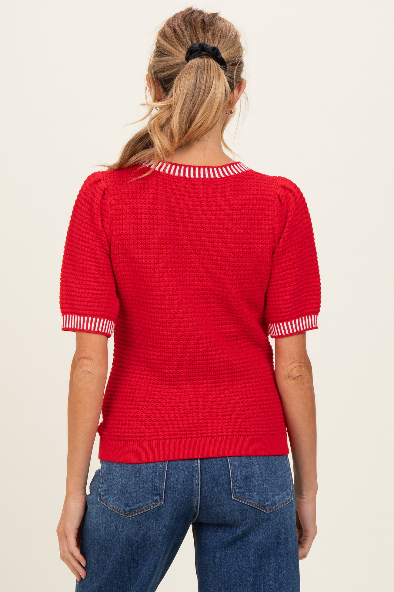 woman wearing a red maternity sweater with striped collar and short puff sleeves, seen from the back
