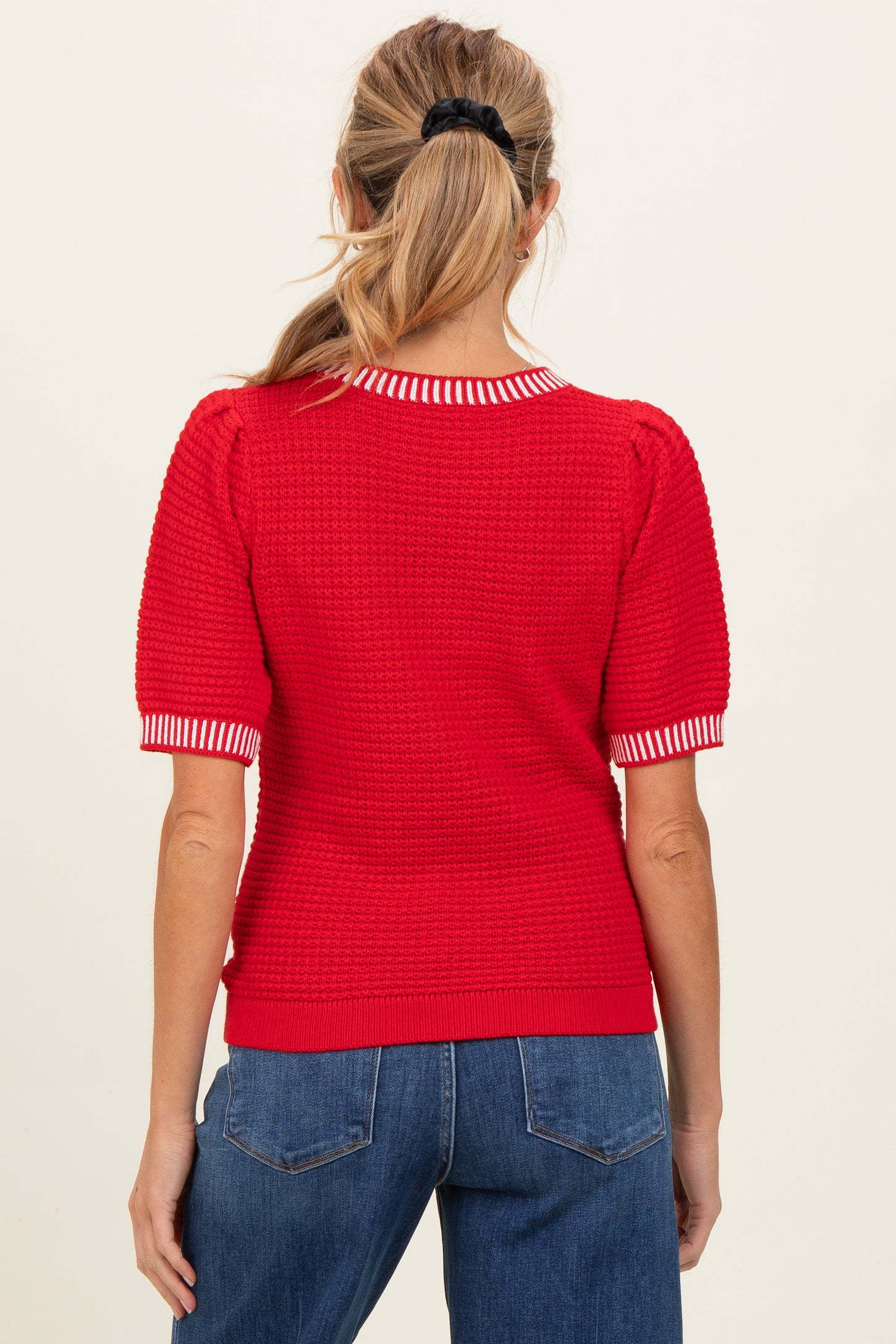 woman wearing a red maternity sweater with striped collar and short puff sleeves, seen from the back