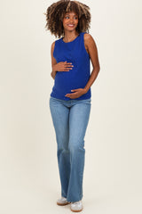 woman wearing a blue sleeveless maternity top and holding her baby bump, paired with light wash flared jeans
