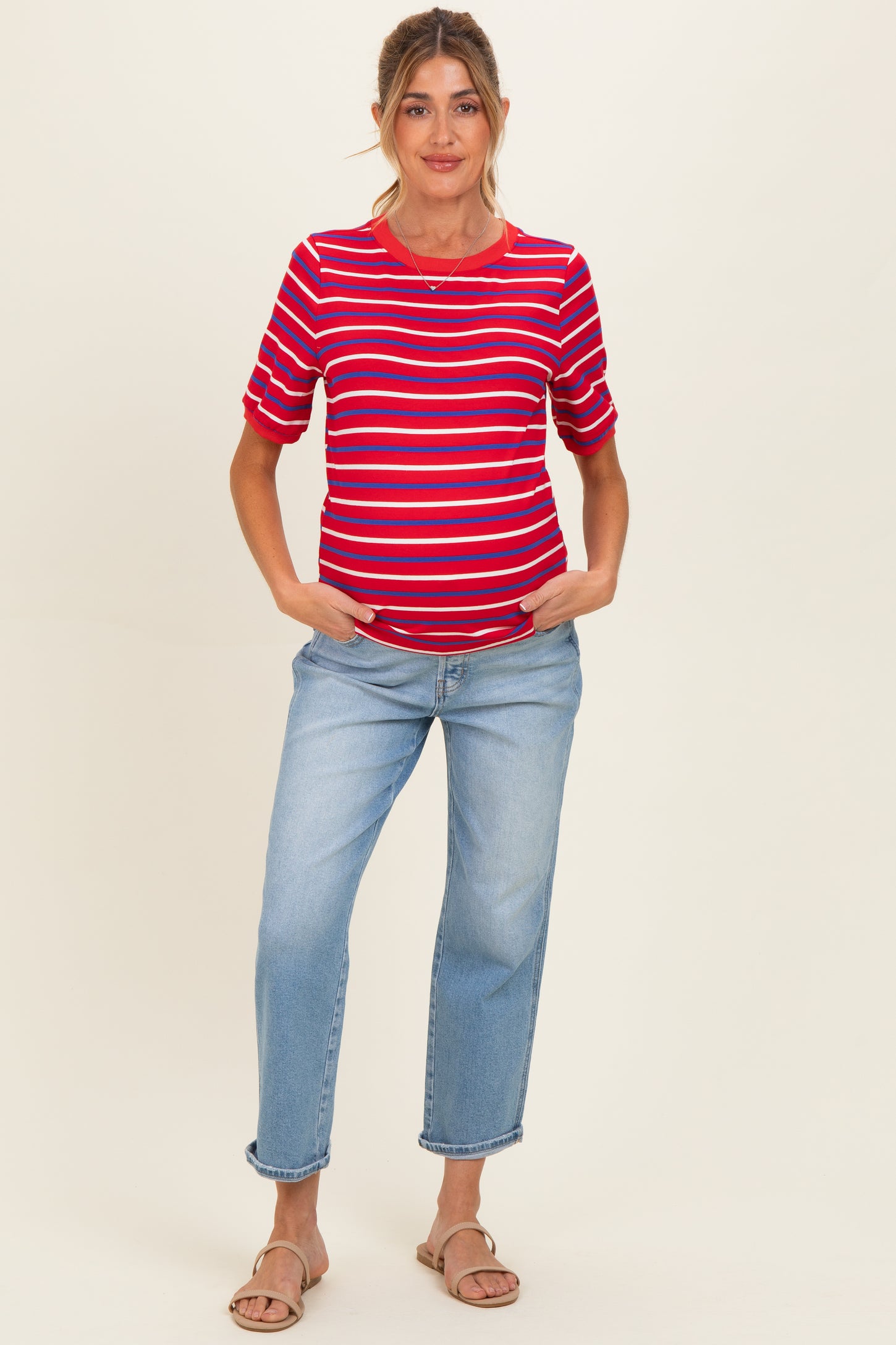 woman wearing a red and blue striped maternity top with rolled sleeves and light wash jeans, showing a baby bump