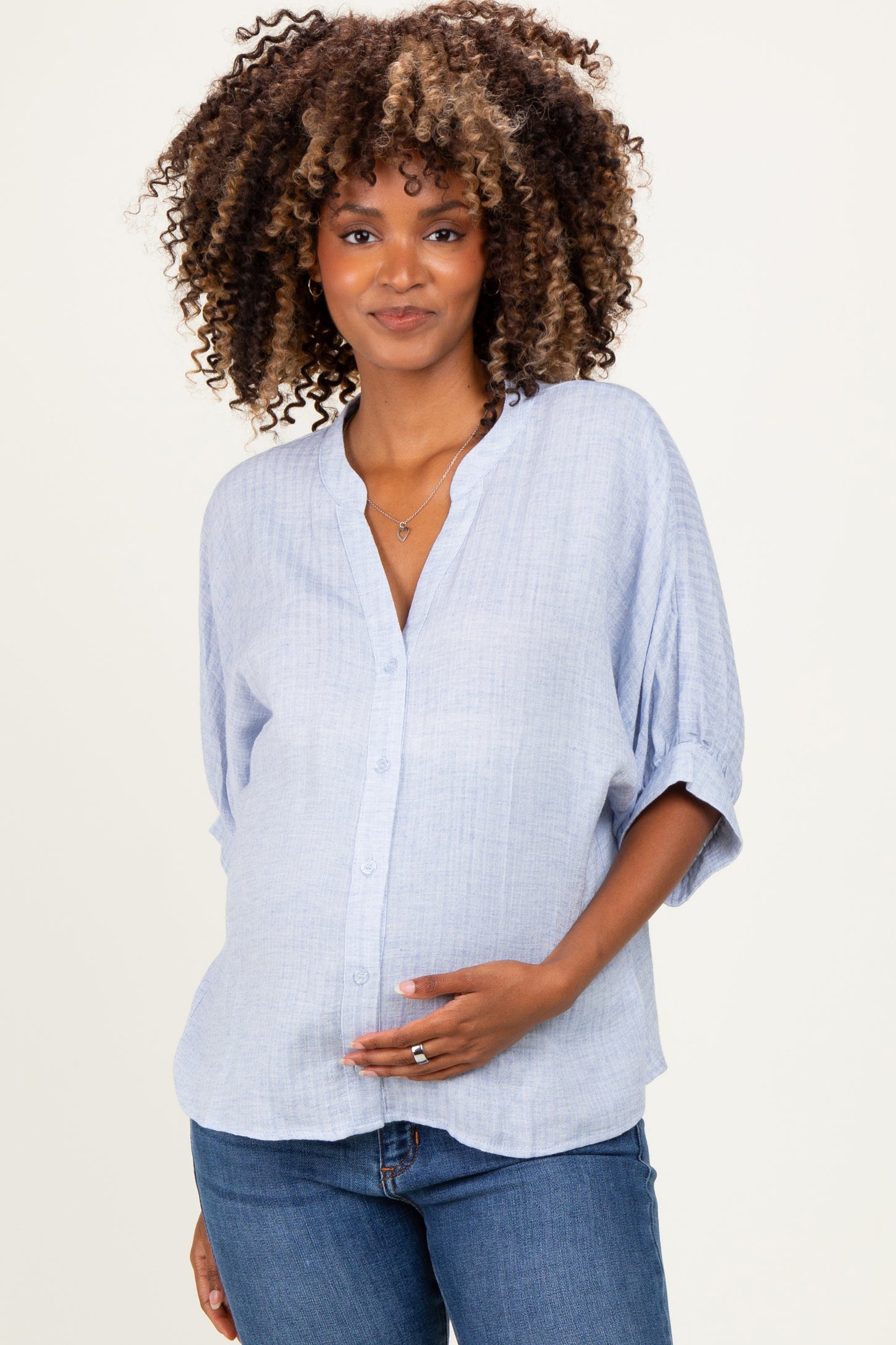 woman wearing a light blue button-up maternity shirt and holding her baby bump