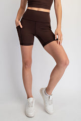 woman wearing brown high-waisted bike shorts with pockets and white sneakers