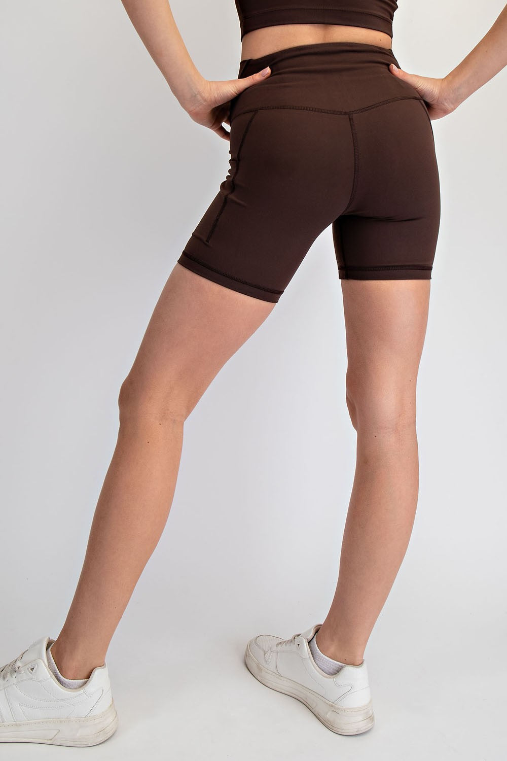 woman wearing brown high-waisted athletic shorts, viewed from the back, with a fitted style and side pocket