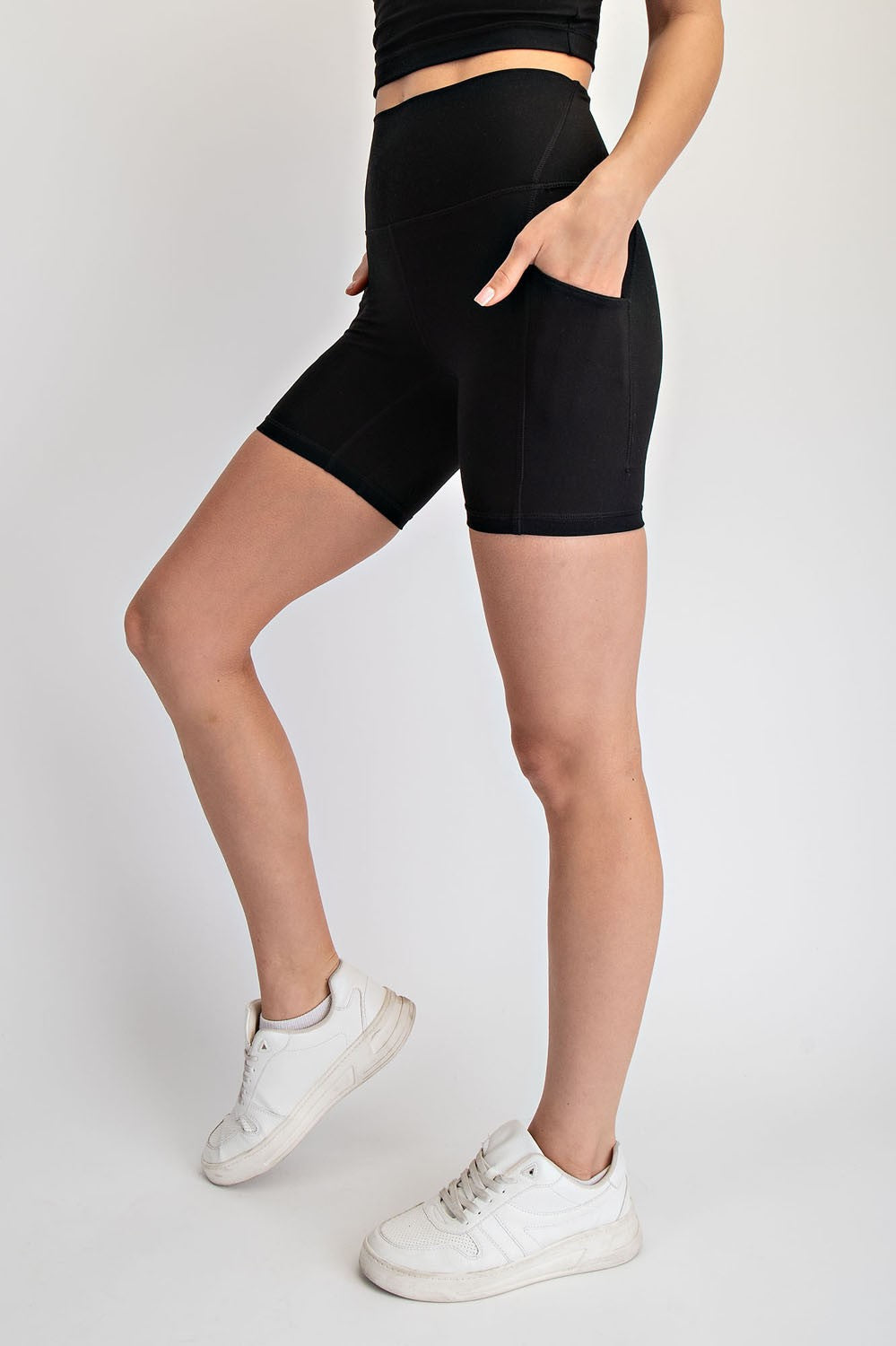 woman wearing black high-waisted biker shorts with side pockets and white sneakers