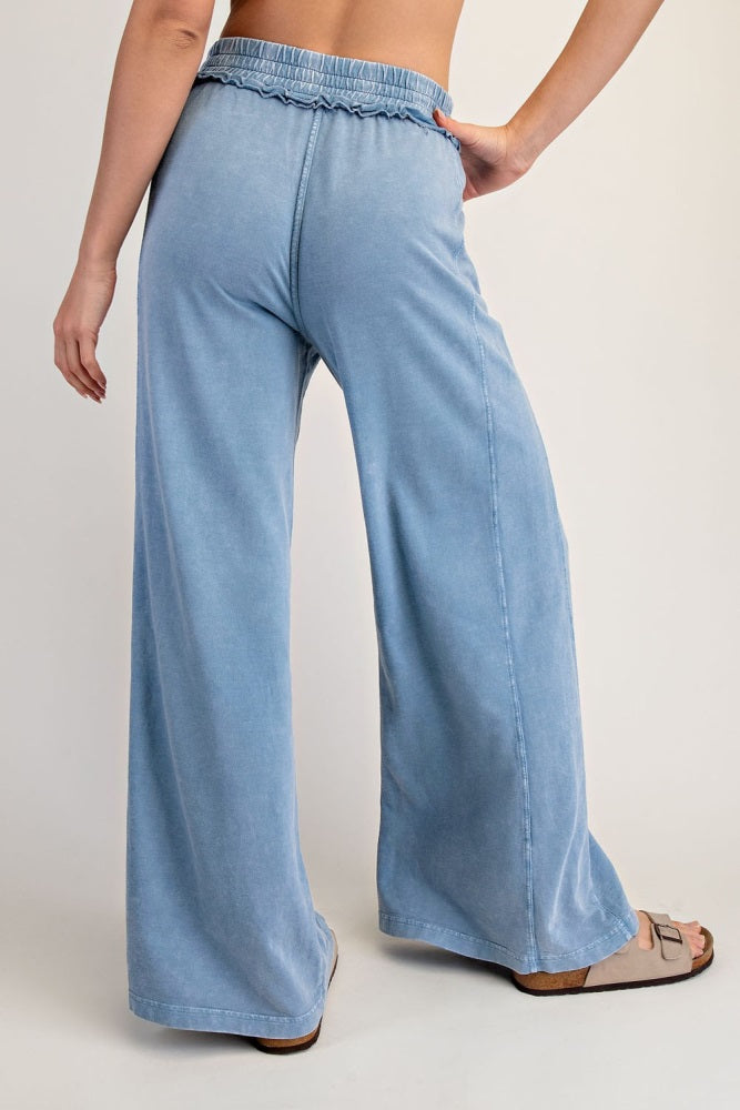 woman wearing light blue wide-leg pants with an elastic waistband and ruffled detail, shown from the back
