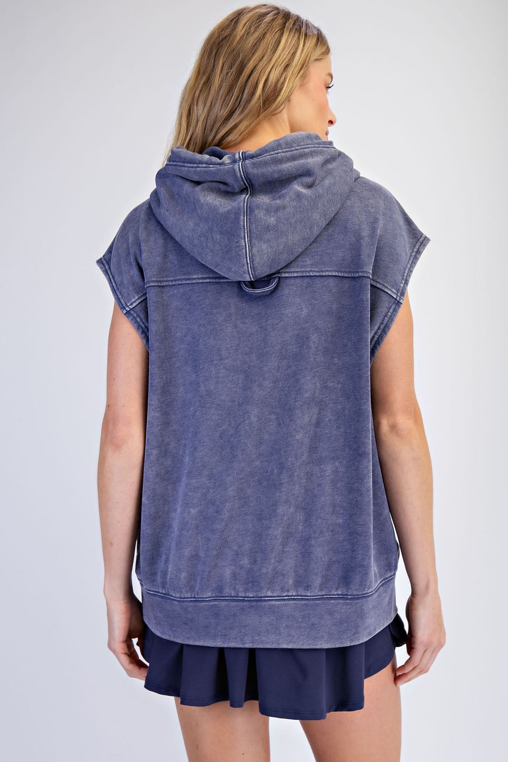 woman wearing a navy blue sleeveless hoodie with a hood, shown from the back