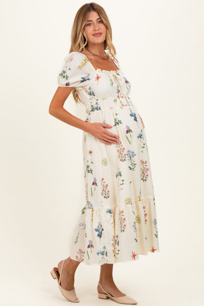 woman wearing a floral print maternity dress with puff sleeves and a ruffled hem, holding her baby bump