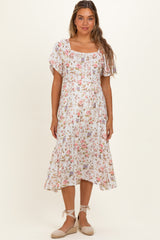 woman wearing a white floral print maternity dress with short flutter sleeves and a tie waist