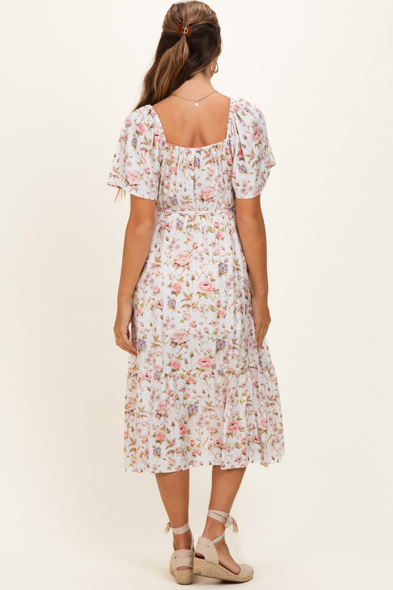 woman wearing a floral midi maternity dress with short puff sleeves and a smocked bodice, showing a baby bump