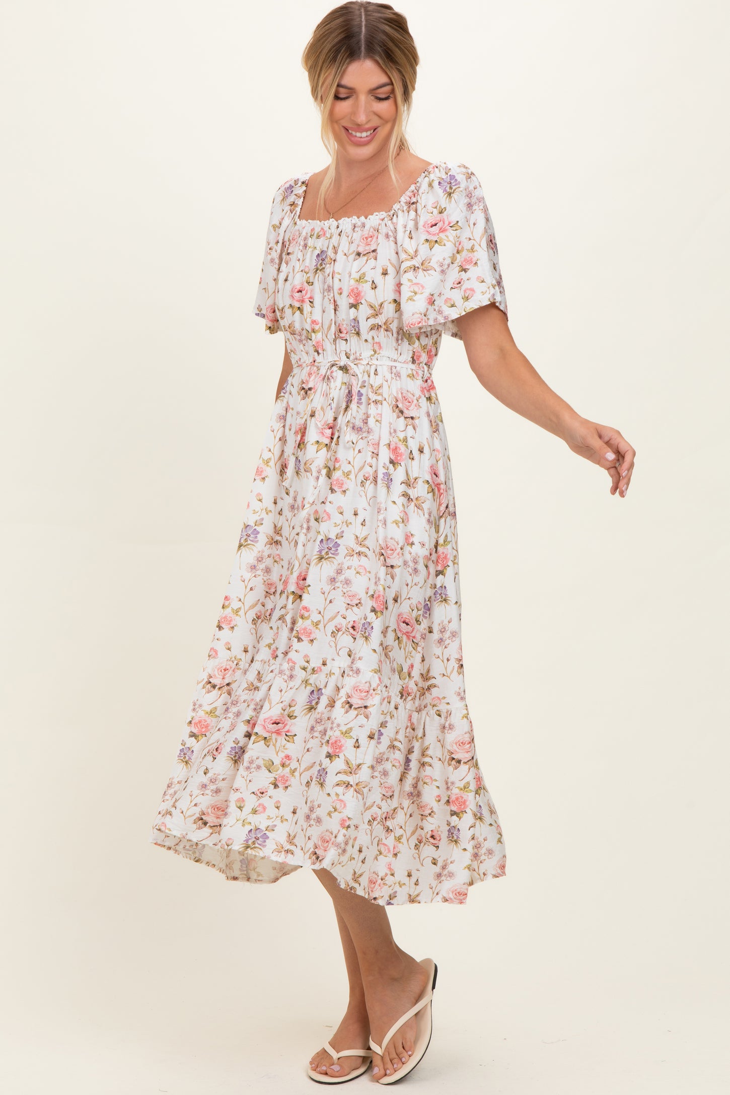 woman wearing a white floral mid-length dress with a square neckline and puff sleeves, smiling and in motion