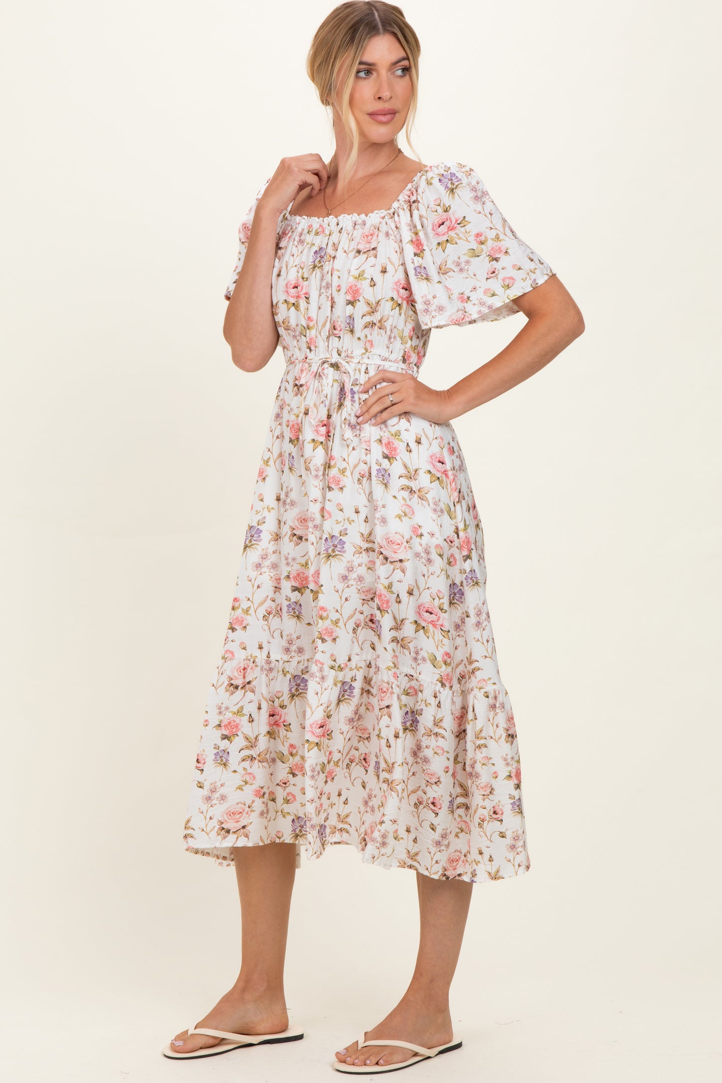 woman wearing a white floral midi dress with puff sleeves and a gathered waist, styled for a casual look