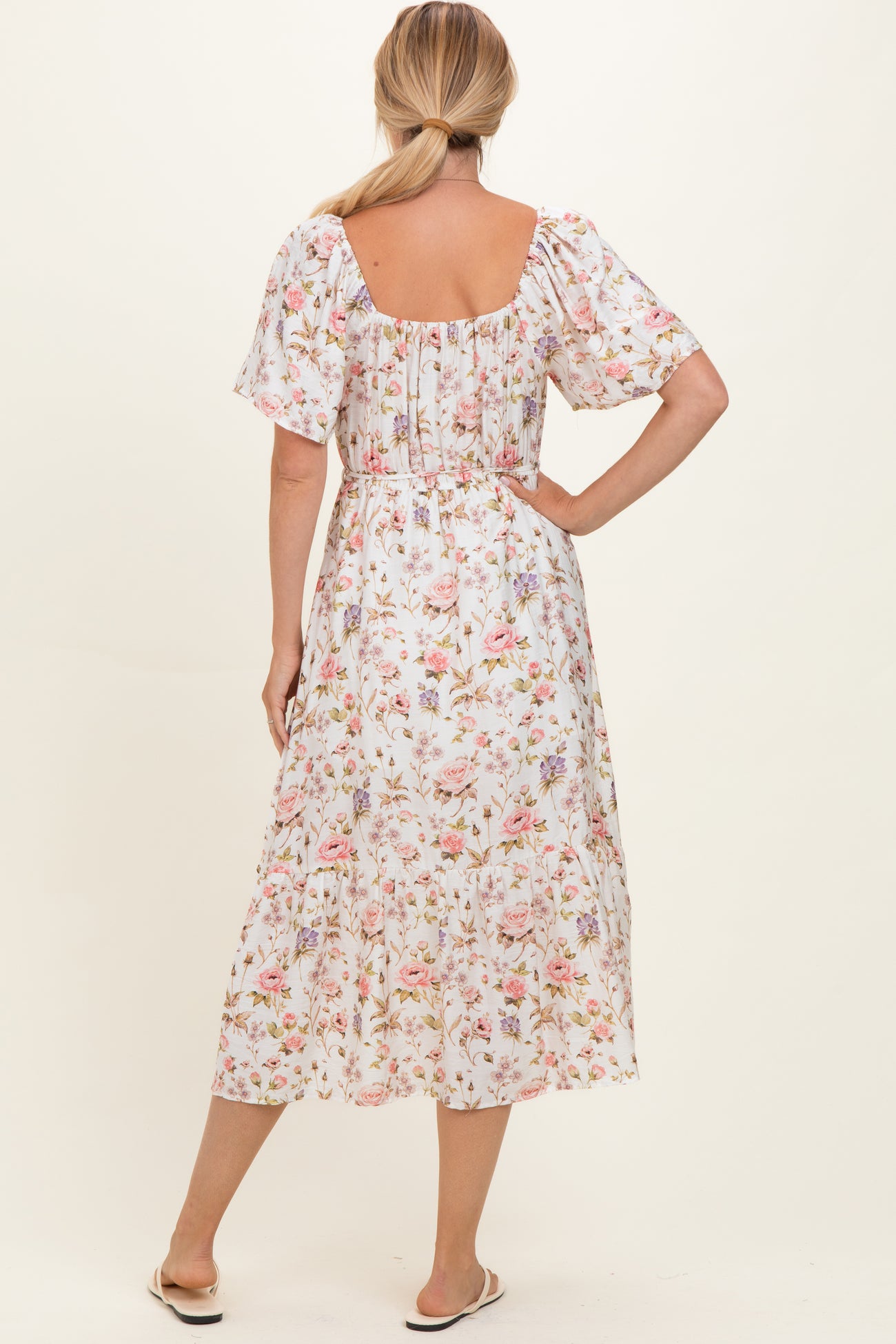 woman wearing a floral midi dress with short sleeves and a smocked back, viewed from the back