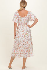 woman wearing a floral midi dress with short sleeves and a smocked back, viewed from the back