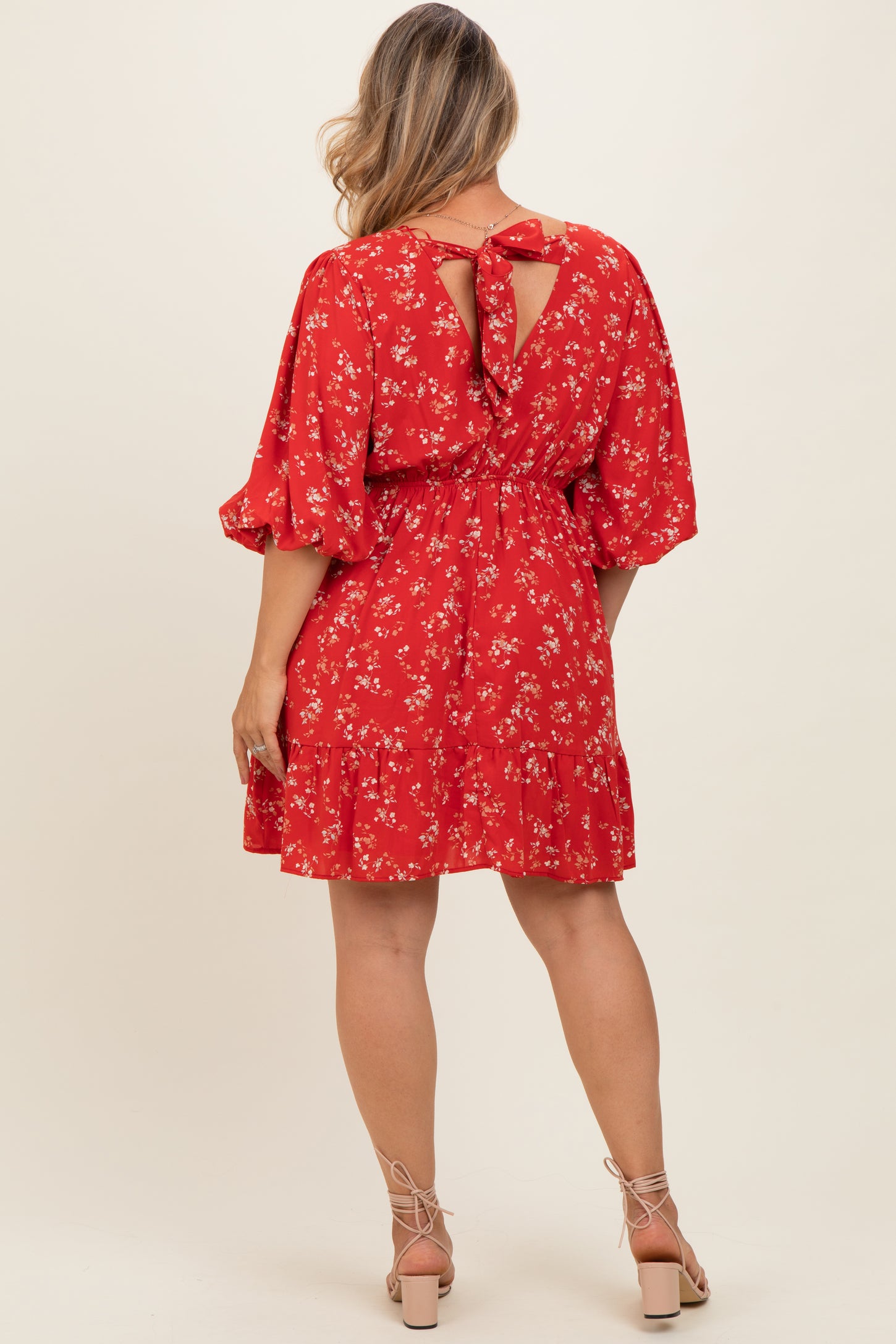 woman wearing a red floral maternity dress with a tie back and ruffle hem