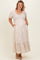 woman wearing a floral maternity plus maxi dress with short puff sleeves and side pockets, displaying a baby bump