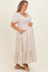 woman wearing a floral maternity maxi dress with short sleeves, v-neck, and pockets, holding her baby bump